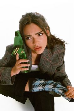 a woman holding a green shoe and looking at the camera while sitting on her knees