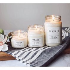 three candles sitting on top of a table next to a white flower and a black and white towel