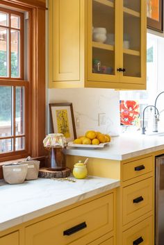 a kitchen with yellow cabinets and white counter tops