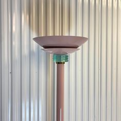 a pink and green lamp sitting on top of a white table next to a metal wall