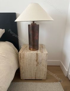 a lamp sitting on top of a wooden block next to a bed