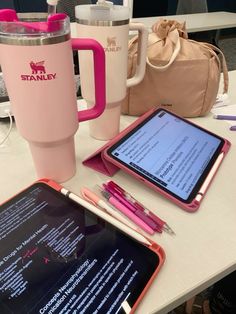 the tablet is next to a pink cup and coffee mug