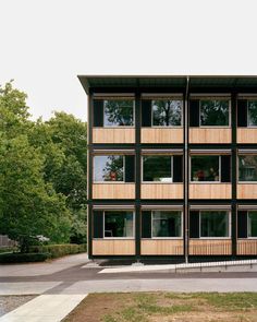 an apartment building with many windows and balconies on the outside, in front of some trees