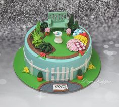 a cake decorated with flowers and a bench in the garden on top of a table