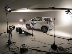 a car is parked on a white surface in front of several lights and camera equipment