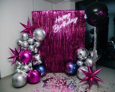 purple and silver balloons are next to a pink birthday banner with stars on it, surrounded by confetti and streamers