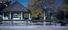 a gazebo in the middle of a park with trees and bushes around it,