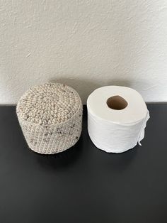 two rolls of toilet paper sitting next to each other on a black countertop in front of a white wall