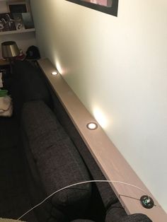 there is a black couch and some lights on the wall