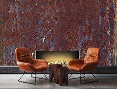 two chairs and a table in front of a rusty wall