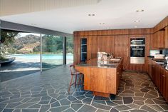 a kitchen with an island counter and wooden cabinets next to a large glass doored window