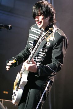 a young man in uniform playing an electric guitar on stage at a music festival or concert