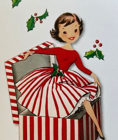 a woman in a red and white dress sitting on top of a box with holly decorations