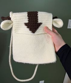 a crocheted purse with a brown and white bear on the front is held up by a woman's hand