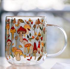 a glass coffee mug with colorful mushrooms on it