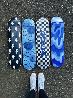 four skateboards are lined up in a row on the pavement, with one person standing next to them