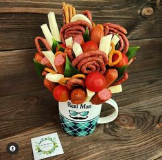 a coffee cup filled with meats, vegetables and fruit sitting on top of a wooden table