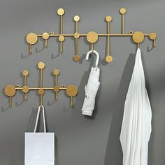 a coat rack with umbrellas hanging from it's hooks on a gray wall