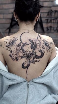 a woman with a snake tattoo on her back, and flowers around the neck is shown