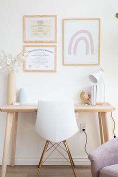 a white chair sitting in front of a wooden desk with pictures on the wall above it