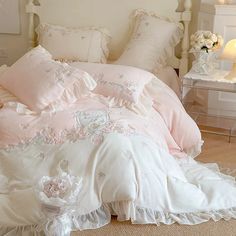 a white bed with pink comforter and pillows