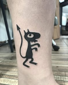 a small tattoo on the leg of a person with a lizard and an arrow in it