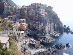 the ocean is blue and clear with houses on it's cliff side, along with rocky shoreline