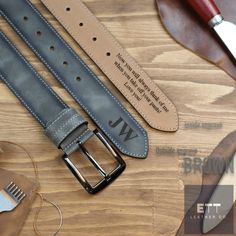 two leather belts are sitting on a wooden table next to some scissors and other accessories