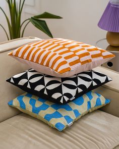 four pillows stacked on top of each other in front of a table with a lamp