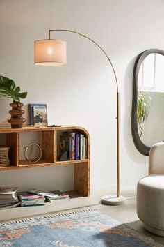 a living room with a lamp, bookshelf and mirror on the wall next to it