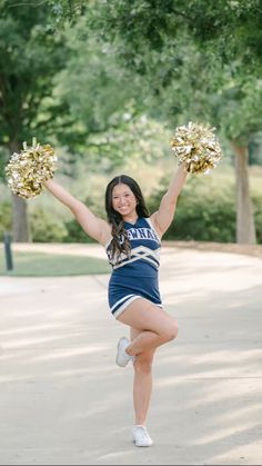 a girl in a cheerleader outfit is holding two pom - poms and posing for the camera