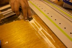 a person using a saw to cut wood with a large piece of metal on the table