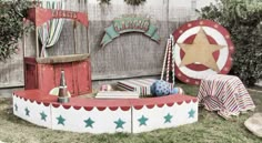 an old fashioned carnival ride with stars and stripes on the top, sitting in front of a wooden fence