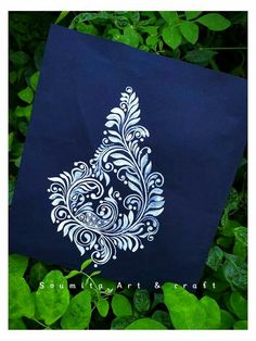 a blue bag with white designs on it sitting in some green leaves and bushes,