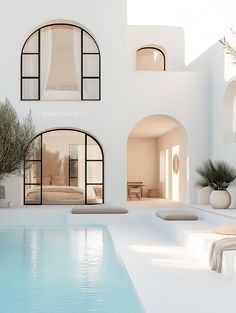 an indoor swimming pool in front of a white building with arched windows on the side