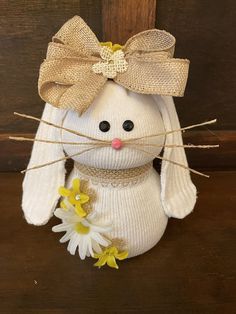 a white stuffed animal with a bow on it's head and flowers in its mouth