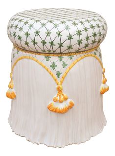 an ornately decorated white stool with gold trimmings and tasselled details