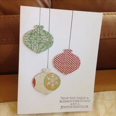 three ornaments hanging from strings on a card