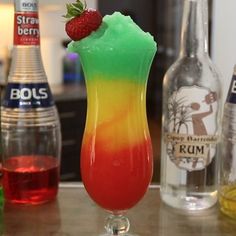 a colorful drink sitting on top of a table next to bottles