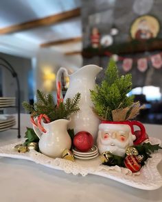 a white pitcher filled with christmas decorations on top of a table