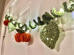 crocheted garland with oranges and green leaves hanging from the side of a door