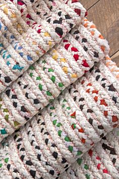 multicolored crocheted blanket laying on wooden floor next to white and black rug