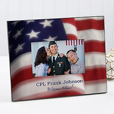 an american flag frame with a soldier kissing his wife on the cheek in front of it