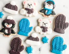 decorated cookies in the shape of mittens, hats, and bears on a marble surface