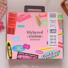 a pink box with stickers on it sitting next to a pair of scissors and other items