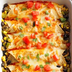 mexican chicken enchilada casserole in a white dish with corn and black beans