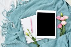 an ipad and flowers on a blue blanket