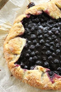 a pie with blueberries on it sitting on wax paper