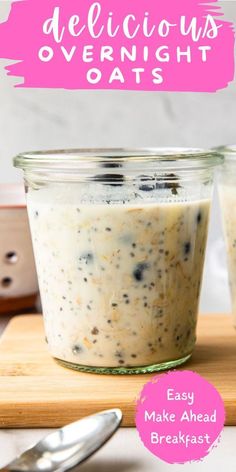 two jars filled with overnight oats sitting on top of a cutting board next to a spoon