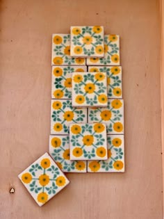 some yellow and green flowers are on the wall next to small tiles that look like they have been made out of tile